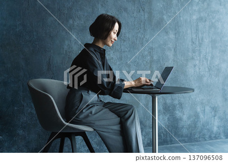 Woman using a laptop at a table Lifestyle image 137096508