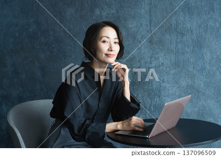 Woman using a laptop at a table Lifestyle image Woman using a laptop at a table Lifestyle image 137096509