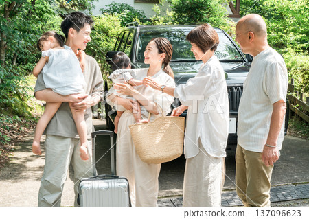 Mother and father holding their granddaughter who has returned home and parents welcoming her (homecoming, three-generation family) 137096623