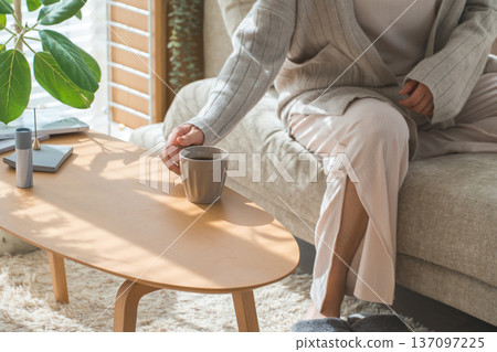 Stylish Asian woman drinking morning coffee in the living room Stylish Asian woman drinking morning coffee in the living room 137097225