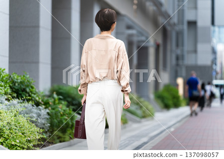 A woman strolling through a city of buildings 137098057
