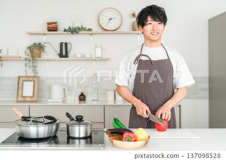 年輕的亞裔男子穿著圍裙在廚房做飯 137098528