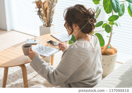 一位穿著時尚的亞洲女性在客廳看雜誌 一位穿著時尚的亞洲女性在客廳看雜誌 137098818
