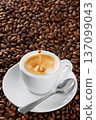 Small white espresso cup with splash and drop, brimming with aromatic coffee resting on bed of roasted beans 137099043