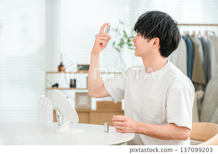 一位年輕的亞洲男子正在往臉上噴灑保養品(男士美容、保濕、乳液) 一位年輕的亞洲男子正在往臉上噴灑保養品(男士美容、保濕、乳液) 137099203