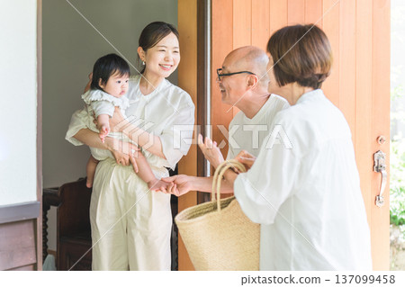 女兒和外孫在前門迎接從鄉下探望的父母。 137099458