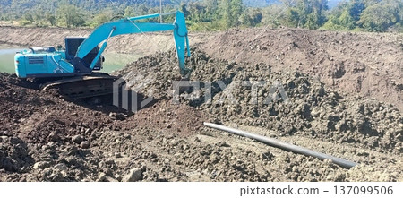 Blue Excavator Working on Earthmoving and Pond Construction Project at a Rural Site Blue Excavator Working on Earthmoving and Pond Construction Project at a Rural Site 137099506