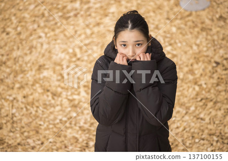 A girl wearing a coat and feeling cold A girl wearing a coat and feeling cold 137100155