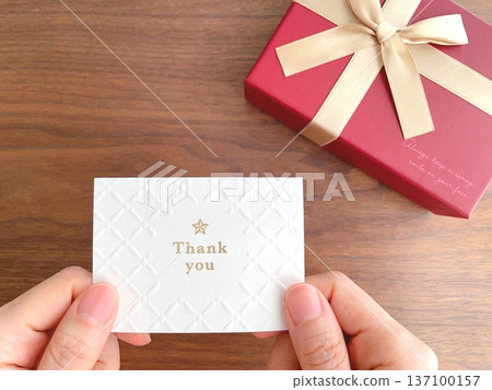 Hands holding a gift box and a message card Hands holding a gift box and a message card 137100157