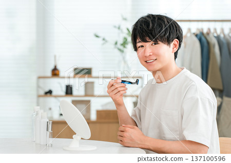Young Asian man shaving with a razor Young Asian man shaving with a razor 137100596