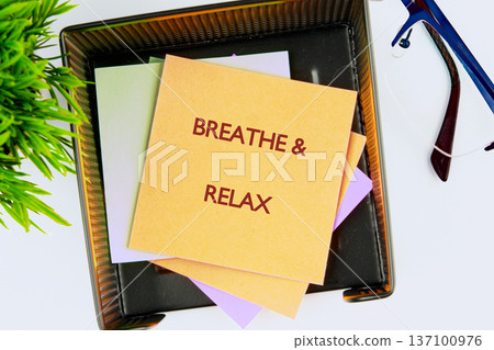 Amber sticky note delivers an essential message to breathe and relax, positioned atop other colorful slips inside a dark mesh organizer Amber sticky note delivers an essential message to breathe and relax, positioned atop other colorful slips inside a dark mesh organizer 137100976