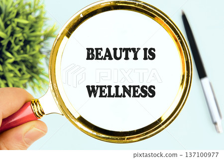 A human hand holds a gleaming magnifying glass, focusing on the powerful message Beauty Is Wellness A human hand holds a gleaming magnifying glass, focusing on the powerful message Beauty Is Wellness 137100977