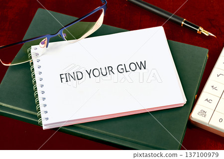 FIND YOUR GLOW notebook on green book, with glasses, pen, calculator, all on a crimson desk FIND YOUR GLOW notebook on green book, with glasses, pen, calculator, all on a crimson desk 137100979