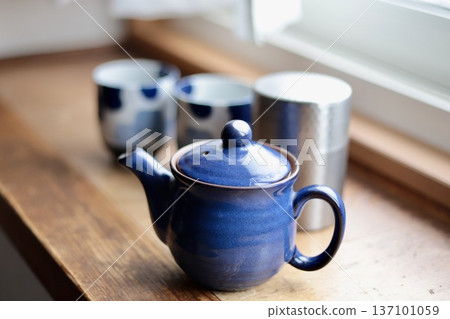一套擺放在窗台上的日本茶具：藍色茶壺、茶葉罐和茶杯。 137101059