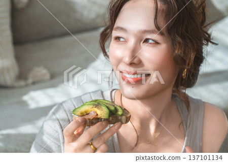 一位時尚的年輕亞裔女性正在客廳餐桌旁用餐。 137101134