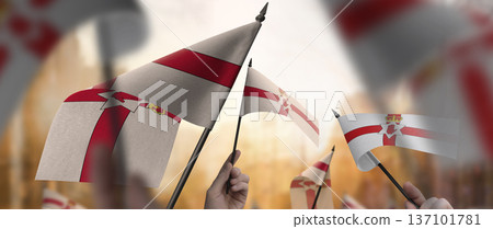 Northern Ireland flags in their hands on a blurred urban background 137101781