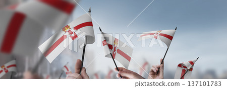 Northern Ireland flags in their hands on a blurred urban background 137101783