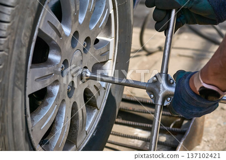 Repair car service.Wheel mounting.Worker tightens nuts on wheel 137102421