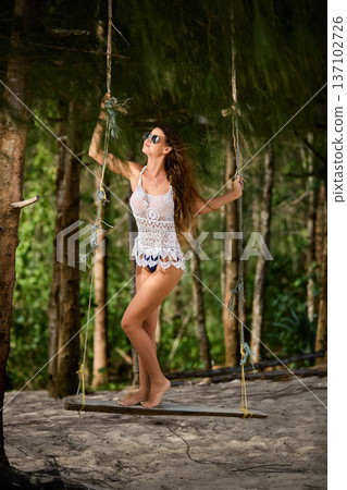 Tropical forest swing portrait of elegant woman in beachwear 137102726
