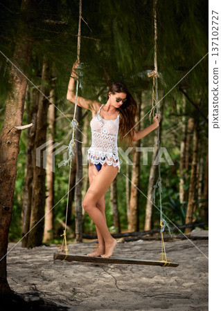 Tropical forest swing portrait of elegant woman in beachwear Tropical forest swing portrait of elegant woman in beachwear 137102727