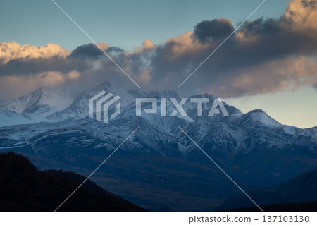 Snow covered mountains at sunset with dramatic clouds in the sky 137103130
