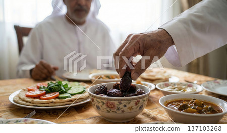Man in white robe serving dates at a traditional Arabic meal 137103268