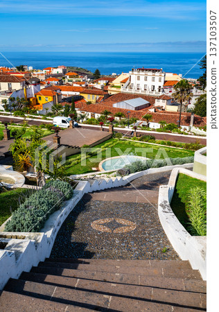 Scenic sunny view down the stone steps of the historic Jardines Victoria terraced gardens towards the traditional town of La Orotava and the ocean in Tenerife, Canary Islands. 137103507