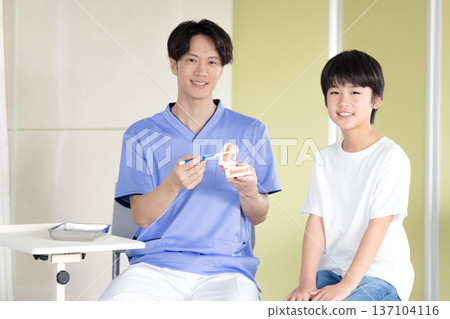 Dentist: Boy and doctor receiving tooth brushing instruction Dentist: Boy and doctor receiving tooth brushing instruction 137104116
