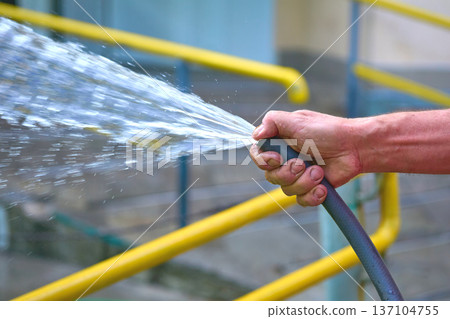 Street and yard cleaning.Stream of water from a hose Street and yard cleaning.Stream of water from a hose 137104755