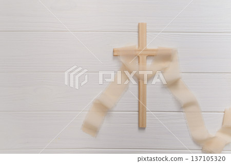 Wooden cross symbolizing christian faith and spirituality, delicate ribbon on a clean copyspace background remembrance for easter Wooden cross symbolizing christian faith and spirituality, delicate ribbon on a clean copyspace background remembrance for easter 137105320