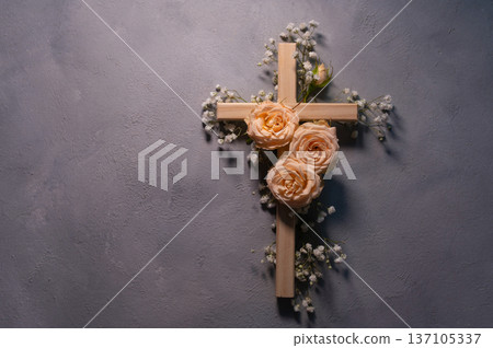 Wooden christian cross with pink roses and gypsophila flowers on a dark shadow wall representing faith and easter faith, resurrection copyspace symbolizing Wooden christian cross with pink roses and gypsophila flowers on a dark shadow wall representing faith and easter faith, resurrection copyspace symbolizing 137105337