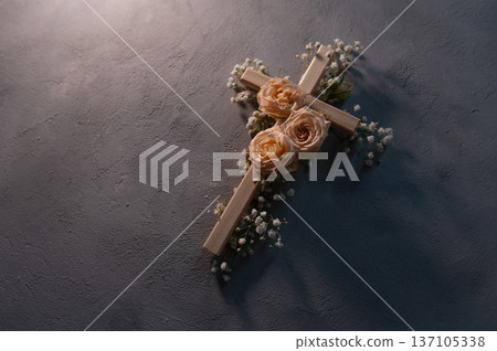 Wooden christian cross with pink roses and gypsophila flowers on a dark shadow wall representing faith and easter symbolizing copyspace faith, resurrection 137105338