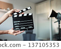 Person holding film clapperboard cueing start of production, motion video or picture, content creation 137105353