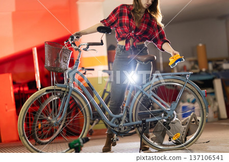 Young woman washing and cleaning vintage bicycle in garage Young woman washing and cleaning vintage bicycle in garage 137106541