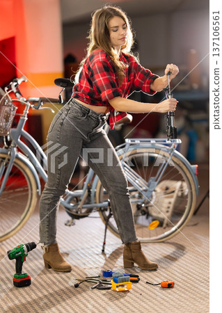 Young woman repairing bicycle demonstrating maintenance skills Young woman repairing bicycle demonstrating maintenance skills 137106561