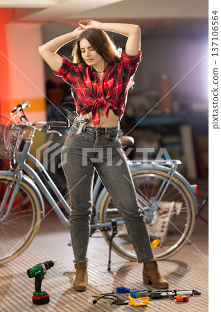 Woman posing with wrenches in workshop near bicycle Woman posing with wrenches in workshop near bicycle 137106564