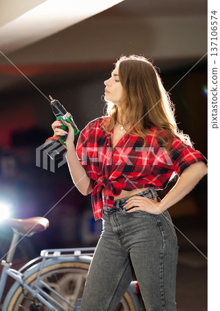 Young woman holding power drill for home improvement project Young woman holding power drill for home improvement project 137106574