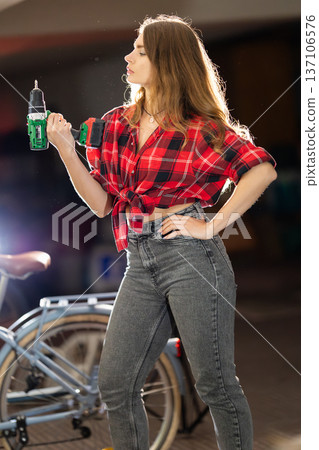 Young woman holding power drill, embracing diy work 137106576