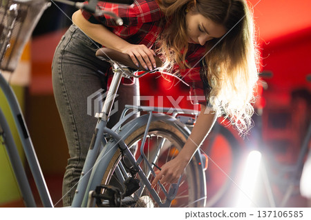 Woman locking bicycle wheel, urban transportation concept 137106585