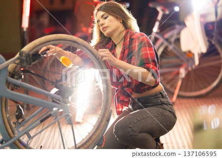 Woman repairing bicycle wheel in a bike workshop 137106595