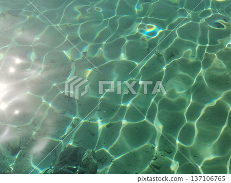 Sunlit clear water surface with green rippling reflections and light pattern for abstract background and texture design 137106765