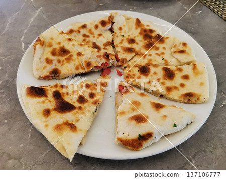 Sliced toasted stuffed flatbread on white plate photographed from angled top for menu background and food presentation for restaurant appetizer Sliced toasted stuffed flatbread on white plate photographed from angled top for menu background and food presentation for restaurant appetizer 137106777