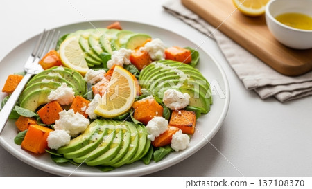 Sliced avocado and roasted squash salad with lemon wedges and ricotta for healthy menu layout and food banner design 137108370