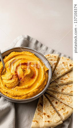 Smooth roasted pumpkin hummus in a ceramic bowl with pita wedges for autumn recipe background and food blog banner use 137108374