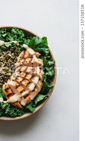 Grilled chicken and kale bowl with creamy dressing and sweet potato mash for healthy dinner bowl background and food blog overhead image 137108516