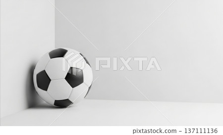 Black and white soccer ball sitting in modern minimalist corner with clean geometric shadows and neutral gray background 137111136