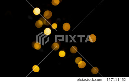 Golden bokeh lights on black background, festive and abstract blurred circles, warm holiday atmosphere Golden bokeh lights on black background, festive and abstract blurred circles, warm holiday atmosphere 137111462