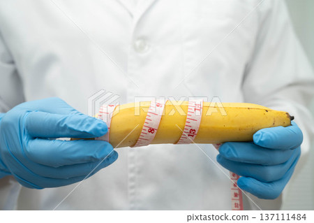 Male doctor stands holding a banana, penis health. 137111484