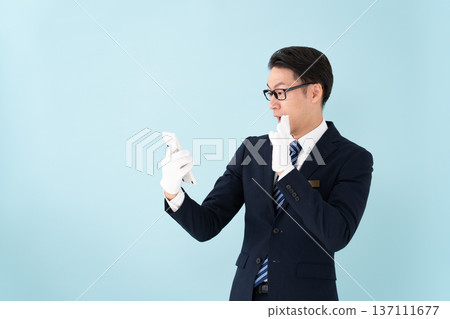 A man wearing white gloves holding a calculator is surprised 137111677
