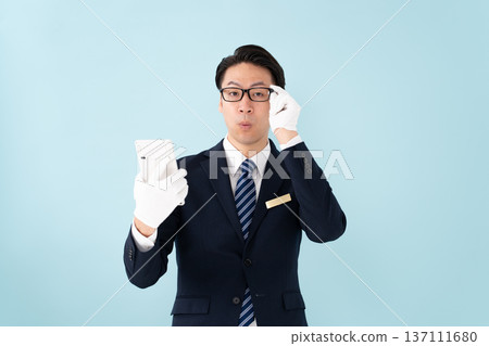 A man wearing white gloves holding a calculator is surprised A man wearing white gloves holding a calculator is surprised 137111680